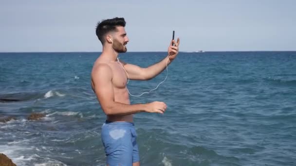 Bonito homem fazendo videochat no mar — Vídeo de Stock