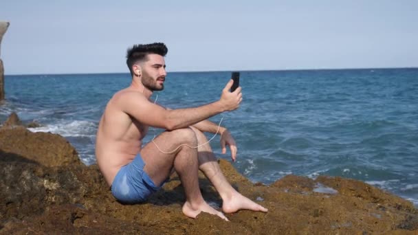 Hombre guapo haciendo videochat en el mar — Vídeo de stock