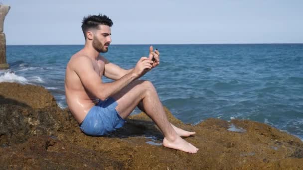 Ung man vid havet tar selfie foto — Stockvideo