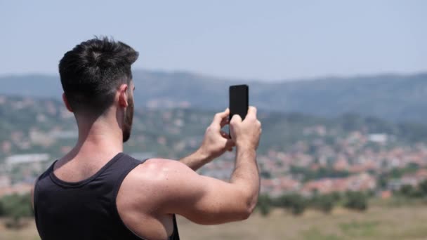 Mladý muž pomocí mobilního telefonu na focení krajiny — Stock video