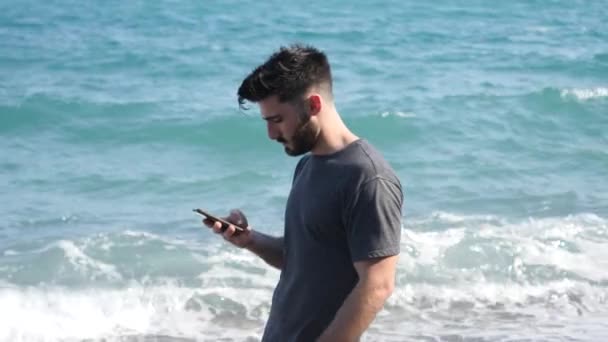 Joven junto al mar enviando un mensaje de voz por teléfono — Vídeo de stock