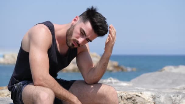 Mladý muž sedí na pláži sám a sám — Stock video