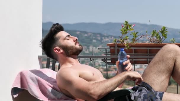 Jeune homme bronzant et aspergeant d'eau sur lui-même — Video