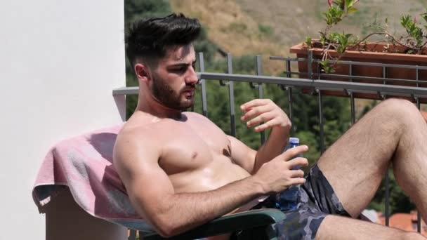 Jonge Man Sunbathing en beregening water op zichzelf — Stockvideo