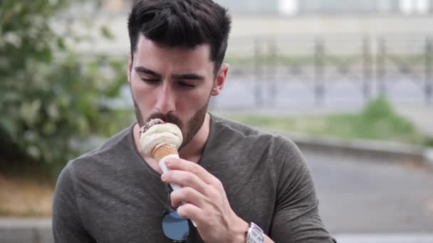 Молодий чоловік стоїть, їсть смачне морозиво — стокове відео