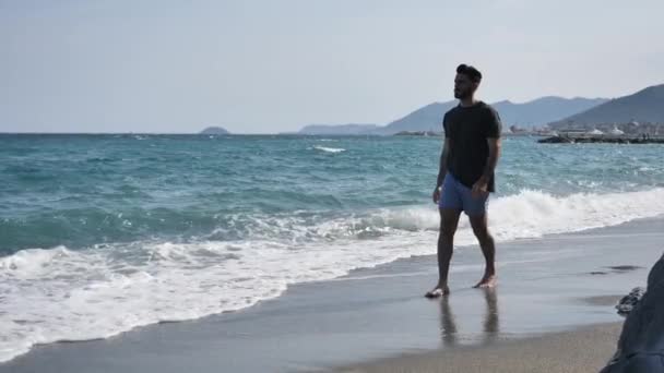 Junger Mann läuft allein am Strand herum — Stockvideo