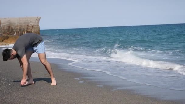 Jeune homme athlétique marchant sur la plage — Video