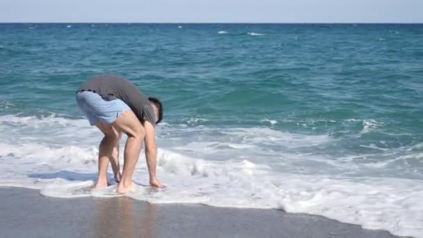 Ung atletisk man promenader på stranden — Stockvideo