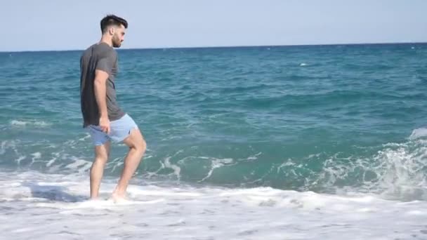 Giovane uomo sulla spiaggia saltando pietre sul mare — Video Stock