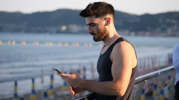 Jeune homme au bord de la mer prenant des photos selfie — Video