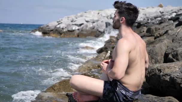 Junger Mann meditiert oder macht Yoga-Übungen auf dem Meer — Stockvideo