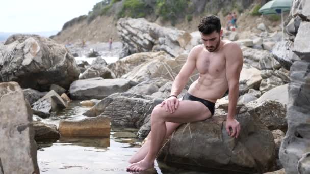 Jovem sentado em uma praia sozinho — Vídeo de Stock