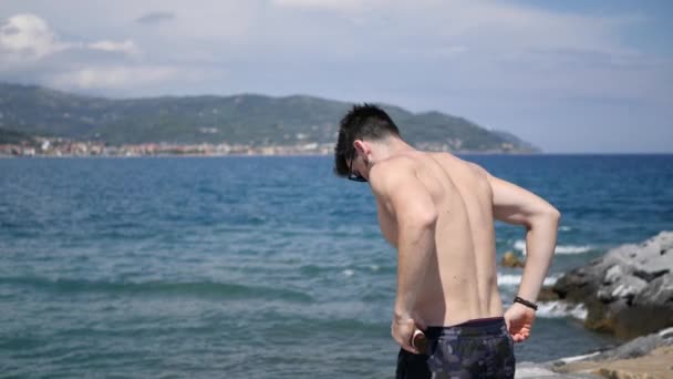 Чоловік ставить на сонцезахисний крем, на пляжі — стокове відео