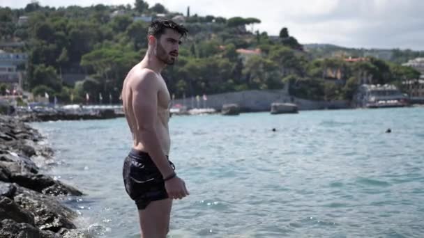 A fiatalember a strandon, merülés a tengerbe — Stock videók