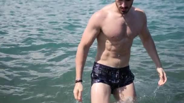 Jonge man op het strand, zwemmen in de zee — Stockvideo