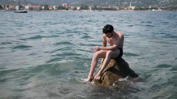 A fiatalember a strandon, fürdéssel a tengerben — Stock videók
