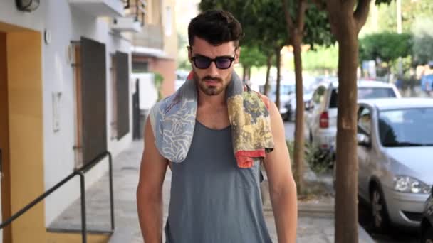 Young man walking in town street in summer — Stock Video