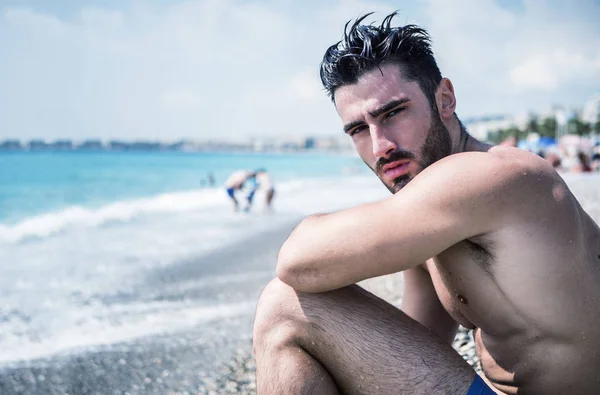 Young man sitting on a beach — Stock Photo, Image