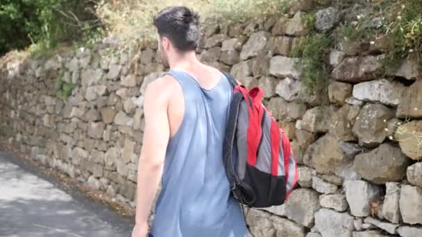 Młody przystojny mężczyzna odkryty piesze wycieczki na wiejskiej drodze — Wideo stockowe