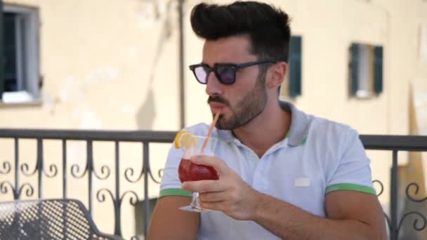 Чоловік п'є коктейль, на відкритому повітрі в барі влітку — стокове відео