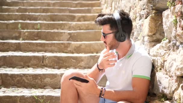 Jovem homem atraente ouvindo música com fones de ouvido — Vídeo de Stock