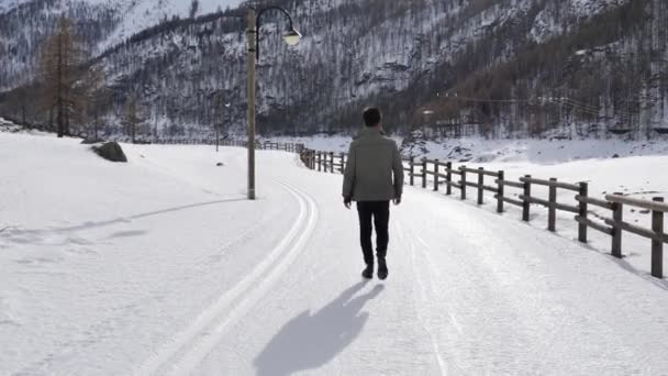 Guapo hombre confiado caminando en la montaña con nieve — Vídeo de stock