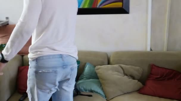 Young man arriving at home and falling on couch — Stock Video