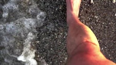 Foaming sea texture background ocean while standing barefoot fine sand beach - Point of view on legs
