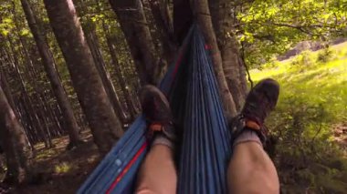 Bir günlük yürüyüşten sonra gün batımında hamakta dinlenen bir adam. Ayak görünümü.