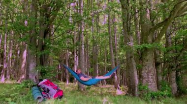 Bir günlük yürüyüşten sonra gün batımında hamakta dinlenen bir adam.