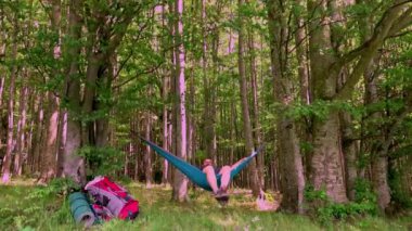 Bir günlük yürüyüşten sonra gün batımında hamakta dinlenen bir adam.