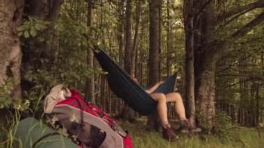 Bir günlük yürüyüşten sonra gün batımında hamakta dinlenen bir adam.