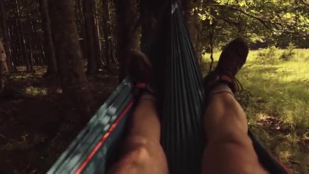 男はハイキングの日の後に山の日没でハンモックでリラックスした 足の眺め — ストック動画