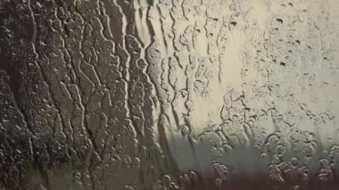 Arkaplanda kara bulutlar olan açık pencereye yağmur damlaları düşer