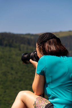 Fotoğrafçı yürüyüşçü, dağların derinliklerinde kamerayla manzara fotoğrafları çekiyor.
