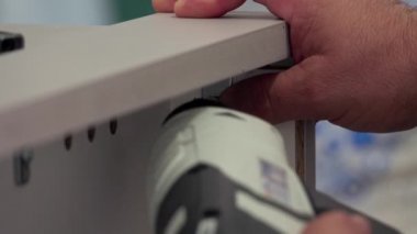 Orta yaşlı bir adam evdeki oturma odasında çeşitli aletlerle mobilya monte ediyor.