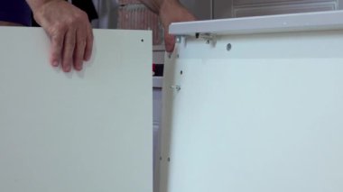 Orta yaşlı bir adam evdeki oturma odasında çeşitli aletlerle mobilya monte ediyor.