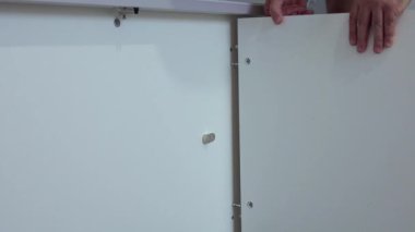 Orta yaşlı bir adam evdeki oturma odasında çeşitli aletlerle mobilya monte ediyor.