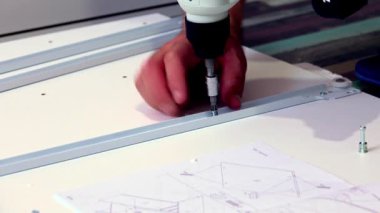 Orta yaşlı bir adam evdeki oturma odasında çeşitli aletlerle mobilya monte ediyor.