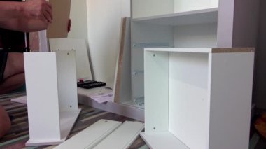 Orta yaşlı bir adam evdeki oturma odasında çeşitli aletlerle mobilya monte ediyor.