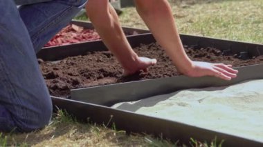 Duyusal bahçede farklı malzemelerden yapılmış bir yol inşa eden küçük çocuklar. Ahşap, saman, kaya, toprak ve kum dokusu. Çiçek bahçesinde yürüyen insanlar. Yakın plan.