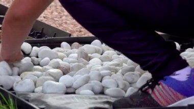 Duyusal bahçede farklı malzemelerden yapılmış bir yol inşa eden küçük çocuklar. Ahşap, saman, kaya, toprak ve kum dokusu. Çiçek bahçesinde yürüyen insanlar. Yakın plan.