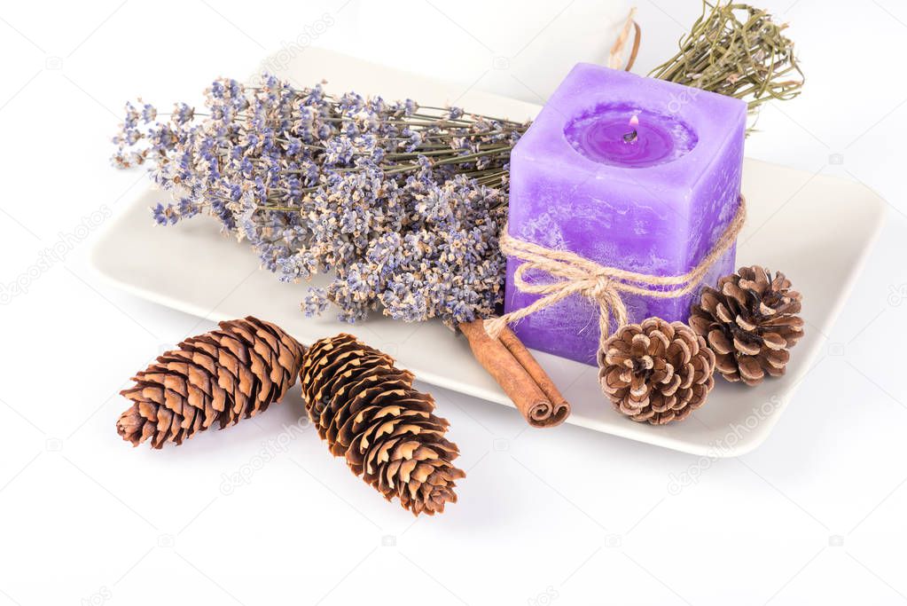Still life with lavender candle, fir cones and dry lavender on a white plate on white background