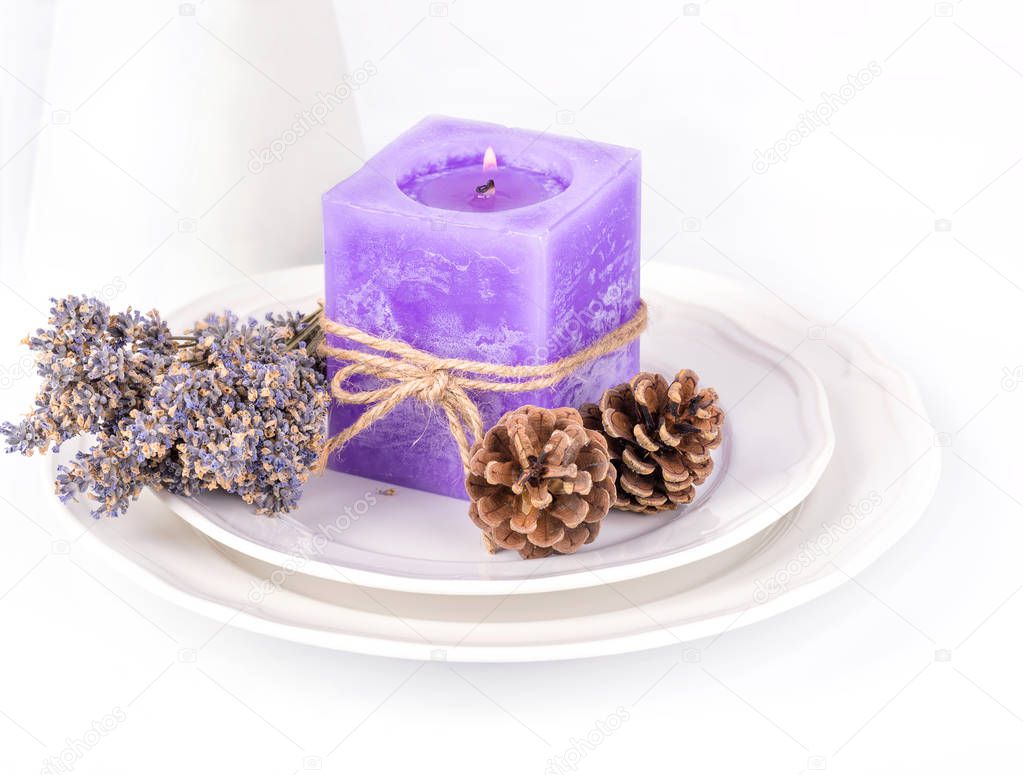 Still life with lavender candle, fir cones and dry lavender on a white plate on white backgroun