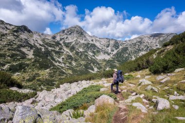 Bir adamın yaz dağda hiking bir sırt çantası ile arkadan görünüş