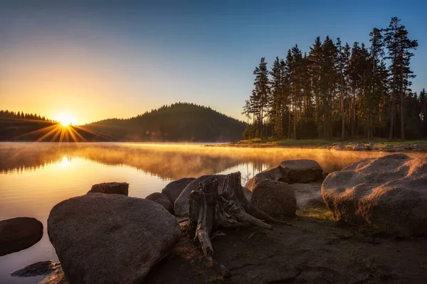 針葉樹に囲まれた山の湖の上に太陽の光が美しい日の出の景色 ブルガリア ロドピ山脈のシロカポリアナダム — ストック写真
