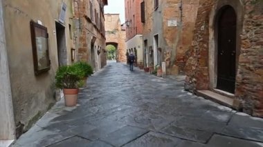 İtalya, Pienza - 11 Nisan 2019: Pienza, Toskana'nın eski pitoresk sokaklarında yürüyen bir adamın arka görünümüyle video