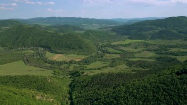 Yeşil çayırlar, ormanlar ve tepeler üzerinde uçan hava görüntüsü bahar zamanı yemyeşil bitki örtüsüyle kaplandı. Doğu Balkan Dağlarının tepeleri arasındaki pitoresk vadi.
