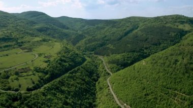 Yeşil çayırlar, ormanlar ve tepeler üzerinde uçan hava görüntüsü bahar zamanı yemyeşil bitki örtüsüyle kaplandı. Doğu Balkan Dağlarının tepeleri arasındaki pitoresk vadi.