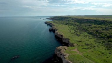 Yeşil alanlar ve ağaçlarla kaplı kayalık kayalık kıyı şeridinin panoramik videosu. Karadeniz kıyısında bahar zamanı, Yailata - Bulgaristan 'ın ulusal arkeoloji ve doğa rezervi.
